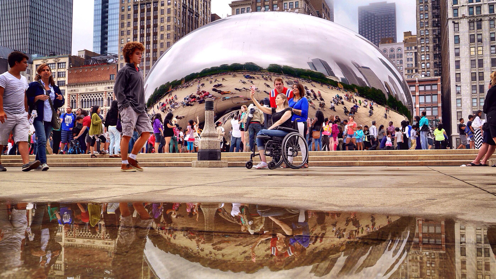 Low ground shot of a woman in front of the Cloud Gate in a wheelchair